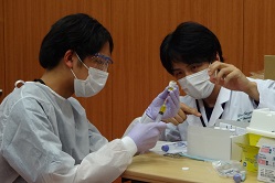 抗がん剤の調剤に挑戦する学生（左）と指導に当たった鈴木医師（右）